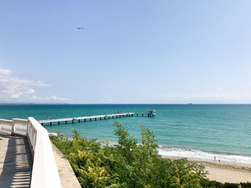 Serene Bulgarian Black Sea coast with pier extending into turquoise waters and peaceful beach
