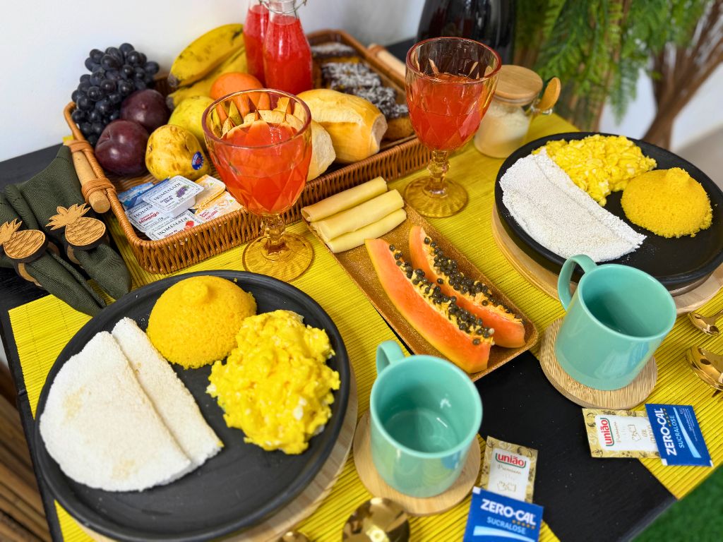 Mesa completa de café da manhã com frutas, sucos e comida típica da Bahia