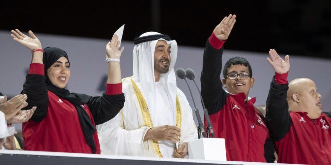 UAE dignitaries with Special Olympics athletes celebrating at opening ceremony, arms raised in triumph