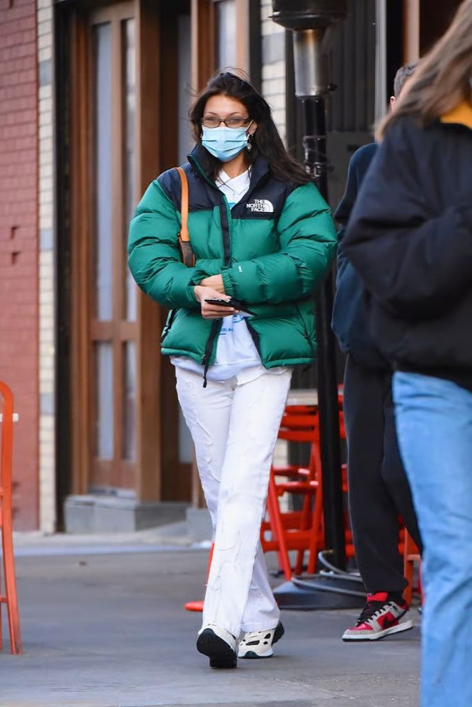 Emerald green puffer jacket with white pants street style