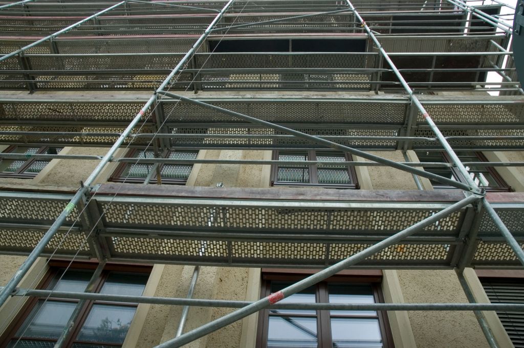 Professionelle Gebäudesanierung Zürich - Gerüstbau und Fassadensanierung an modernem Gebäude mit Sicherheitsausrüstung und fachmännischer Ausführung