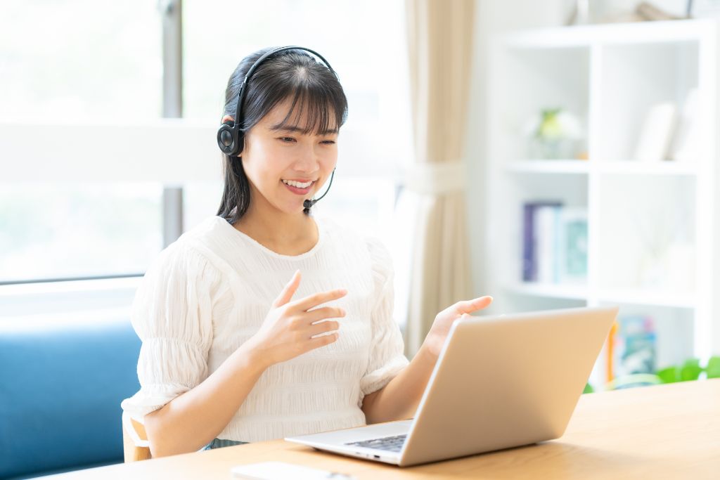 ヘッドセットをつけてPCに向かって話す女性