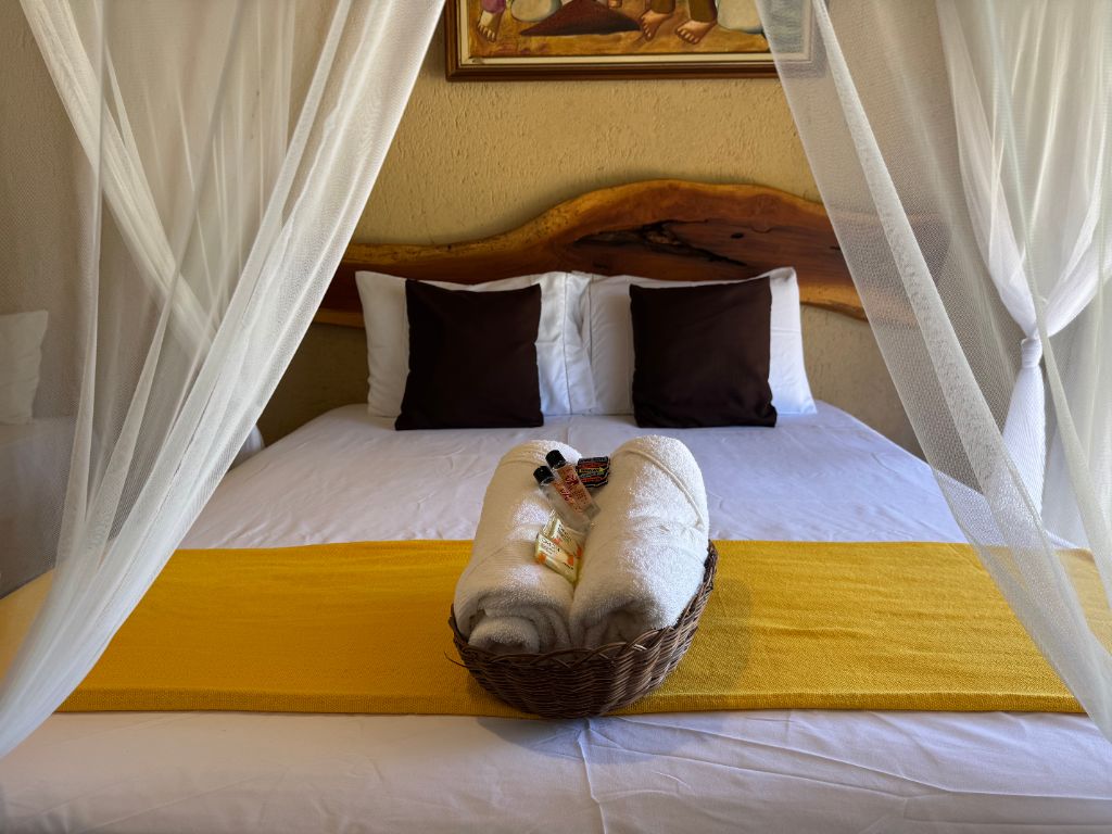 Interior da suíte com cama queen e dossel branco