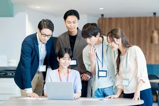 日本人の若手社員がノートパソコンを囲んで笑顔でミーティング