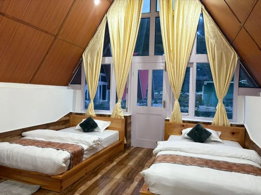 Deluxe room with wooden ceiling, comfortable beds and wicker furniture at Dirang Cozy Home Cottage