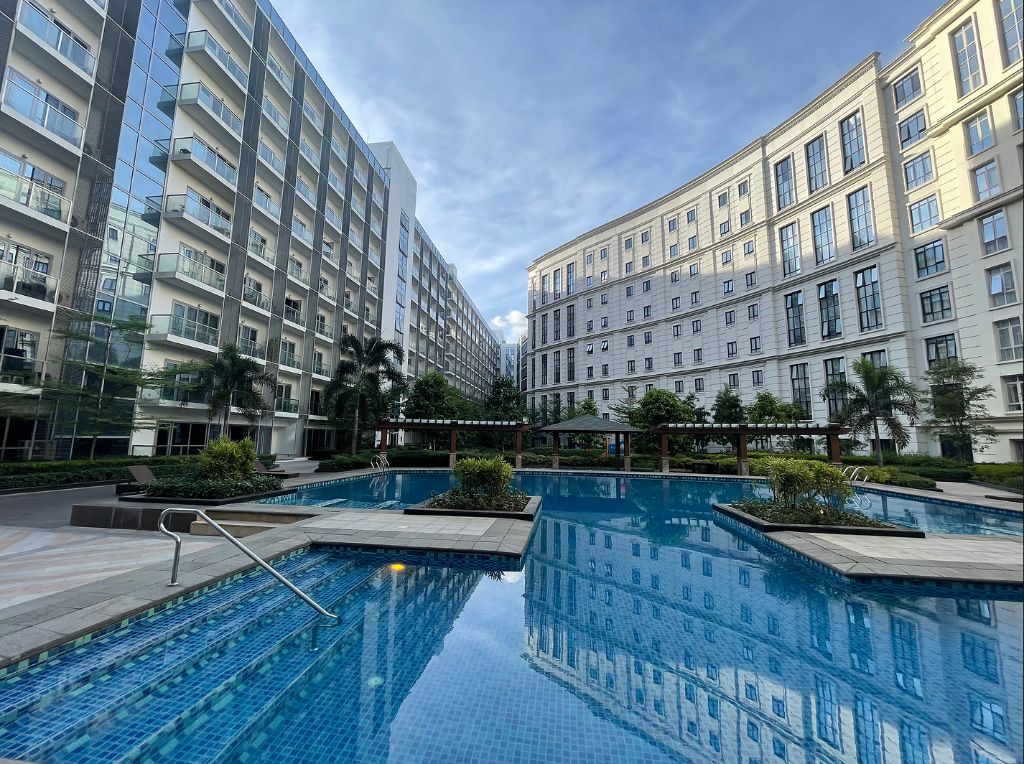 Luxury resort pool area with modern condo buildings and tropical landscaping