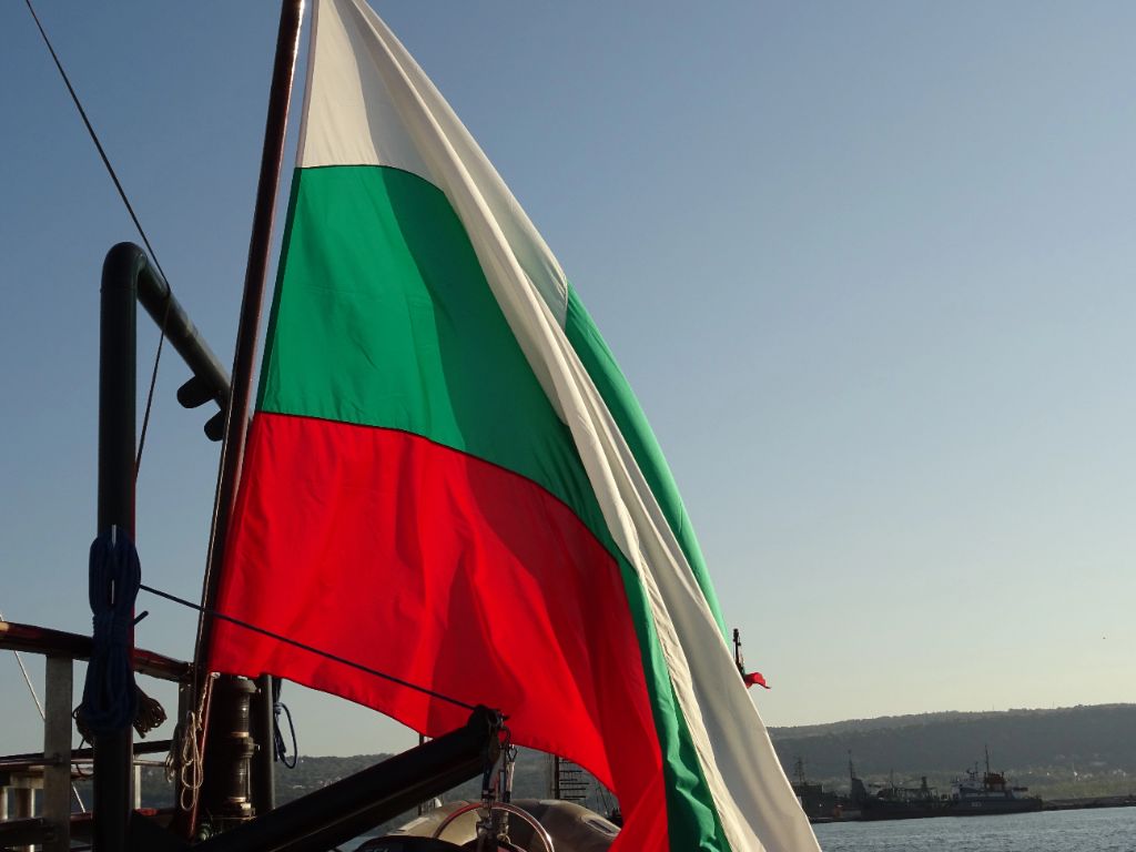 Bulgarian flag proudly displayed with harbor and coastal scenery in the background